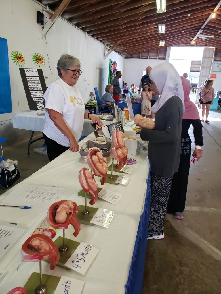 Two women talk while looking at fetal models during the Branch County Fair, 2021.
